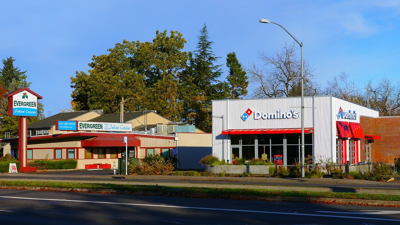 A Dominos pizza store next to a road in the USA